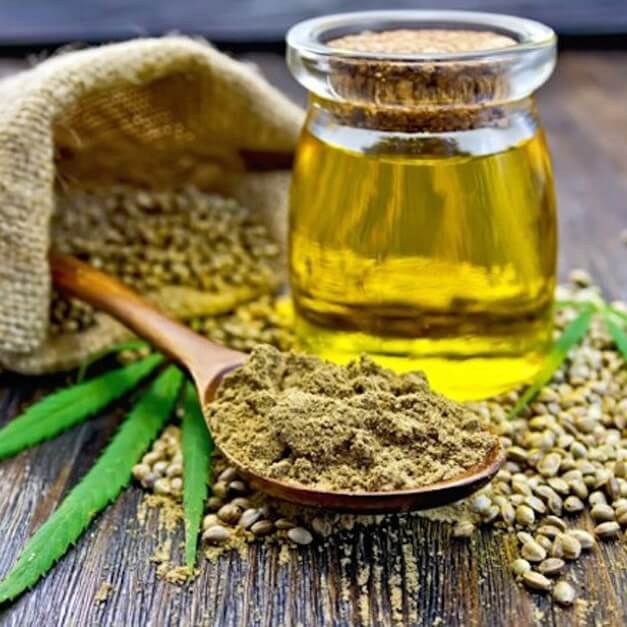 a wooden spoon filled with hemp oil next to a bag of hemp seeds.