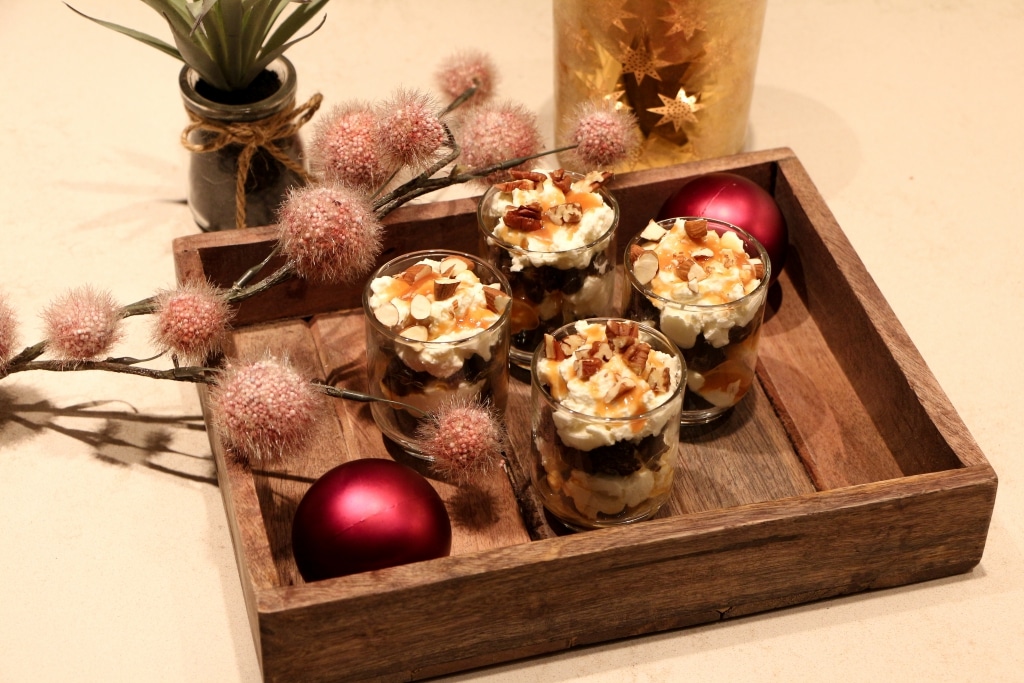 a wooden tray topped with desserts next to a vase of flowers.